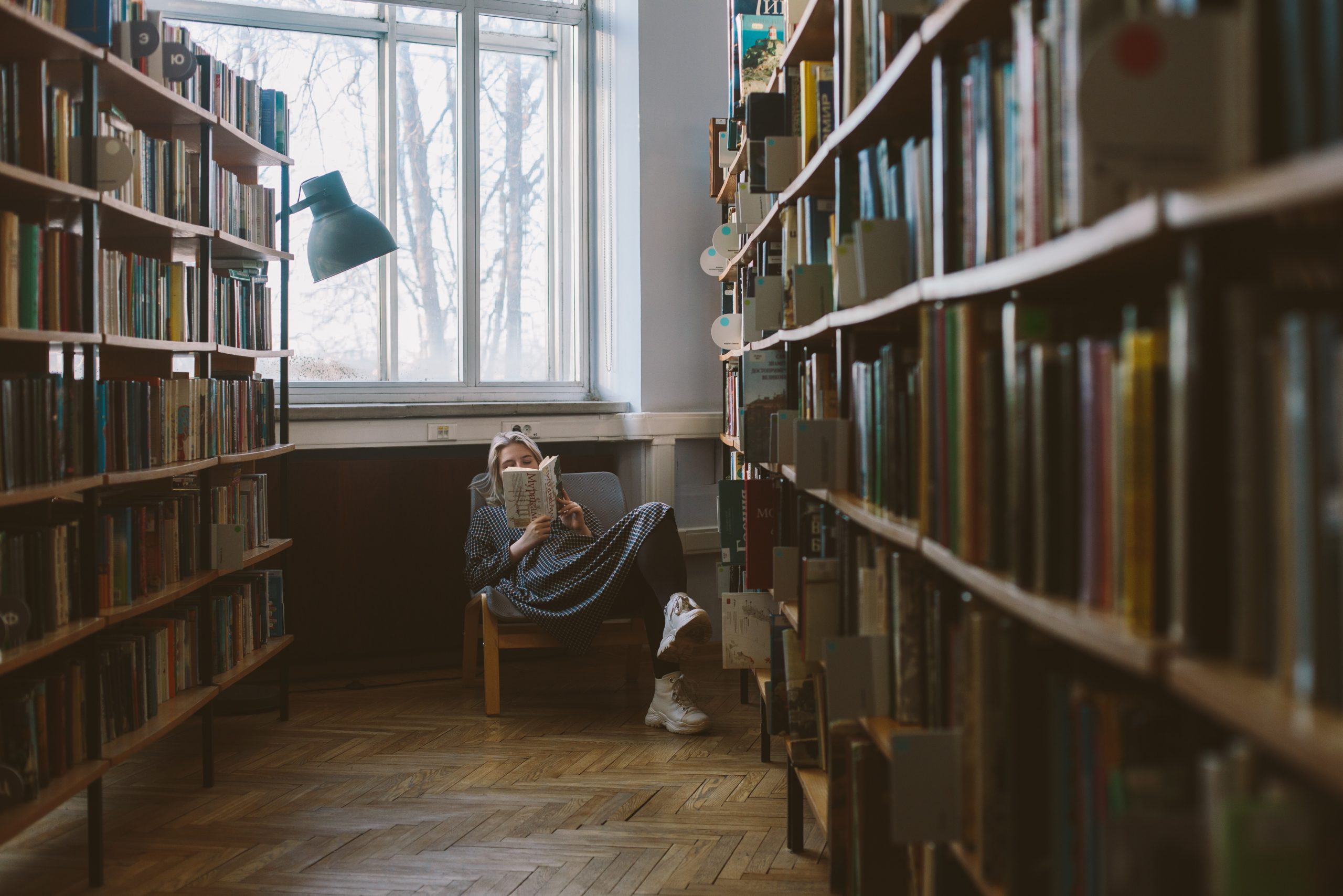 literatura - imagem ilustrativa de mulher lendo em uma biblioteca espaçosa